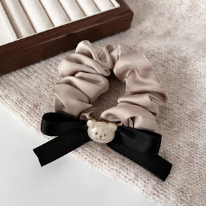 Chouchou en satin champagne avec nœud noir et breloque ours mignon sur tricot beige