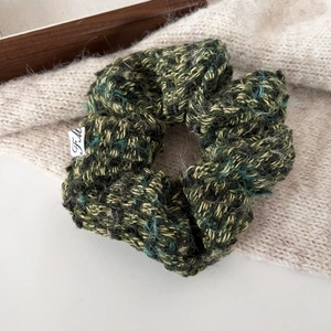 Knitted multicolor scrunchie in green and brown tones with a minimalist logo tag