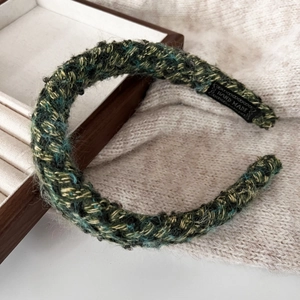 Detailed macro view of handcrafted green knit scrunchie with soft plush texture and handmade label