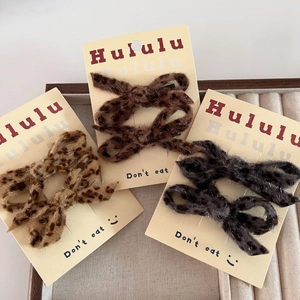 Detail of leopard print plush bow hair clips showing textured fabric and card packaging