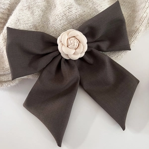 Détail d'un grand nœud marron avec camélia crème sur un fond en maille de qualité