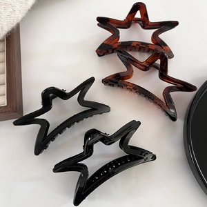 Détails de pinces à cheveux étoiles noires mates et écaille sur un plateau chic