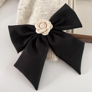 Détail d'une élégante pince à cheveux noeud noir avec une fleur de camélia blanche