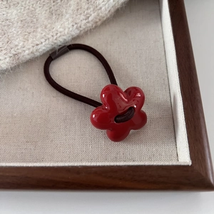 Elegant red floral hair tie with glossy finish and high elastic cord on wood tray