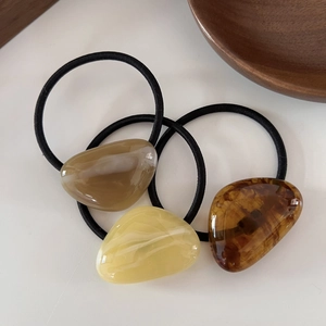 Three-piece geometric hair ties set in amber, beige, and brown colors on white background