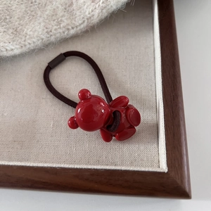 Red resin bear hair tie with high elastic brown band for women on aesthetic wood background