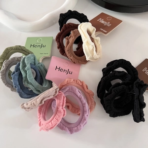 Detailed view of colorful ruffled fabric hair scrunchies with elegant texture on white surface