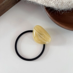 Macro shot of marble texture amber resin bead on high elastic hair tie over white background