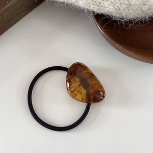 Minimalist amber resin hair tie with geometric brown pattern on an elastic band