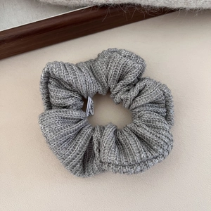 Détail d'un chouchou en maille grise avec texture côtelée et étiquette blanche de marque