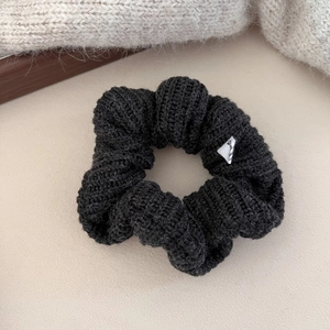 Détail de l'élastique à cheveux en tricot noir avec texture laineuse et petite étiquette