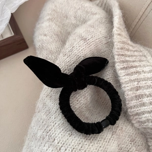 Chouchou élégant en velours noir avec nœud papillon et oreilles de lapin sur fond tricoté