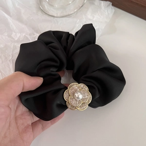 Detail of satin scrunchie featuring a tweed camellia flower with pearl and gold trim