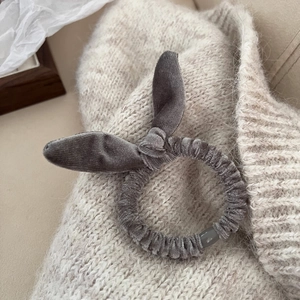 Détail du chouchou en velours gris avec oreilles de lapin sur un pull en maille beige