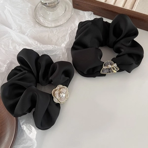 Detailed view of black satin hair scrunchies with camellia pearl and hat charms