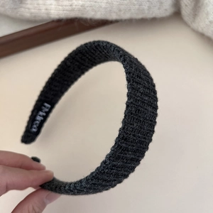 Gros plan du bandeau large en tricot noir avec texture côtelée et étiquette de marque