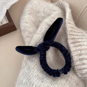 Détail d'un chouchou en velours bleu foncé avec nœud oreilles de lapin sur tricot
