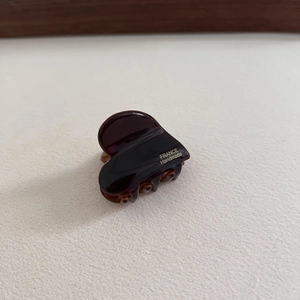 Macro detail of dark brown tortoiseshell heart hair claw with golden France Handmade text