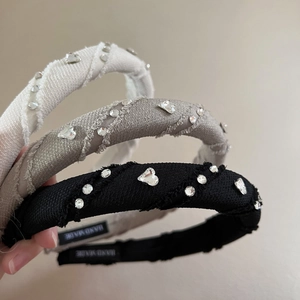 Detail of three rhinestone heart headbands in beige, grey, and black fabric
