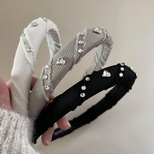 Close-up of three rhinestone heart headbands in beige, grey, and black fabric