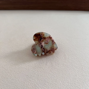 Detailed view of handmade acetate heart hair claw with marble texture and gold lettering