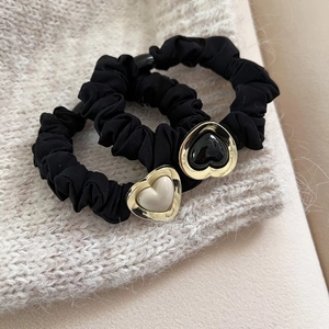 Elegant black scrunchies set with gold-edged heart charms on soft pleated fabric