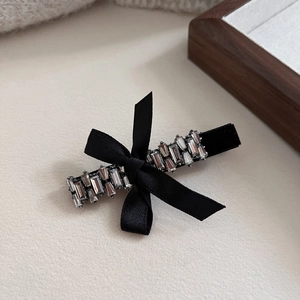 Detailed view of luxury black ribbon hair clip with sparkling crystals and bow accent