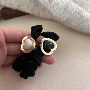 Close-up of black scrunchies featuring gold-rimmed heart charms in black and beige