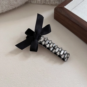 Elegant black bow hair clip with luxury rhinestones and pearls for women in a side view