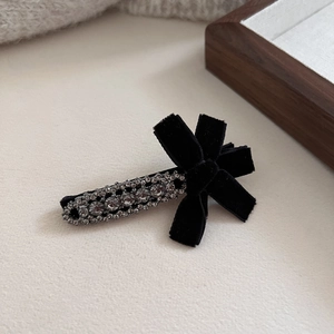 Detail view of a velvet bow hair clip with sparkling rhinestones and black metallic finish