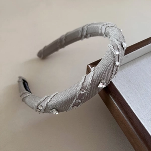 Detail of luxury rhinestone heart headband featuring metallic texture and frayed edges