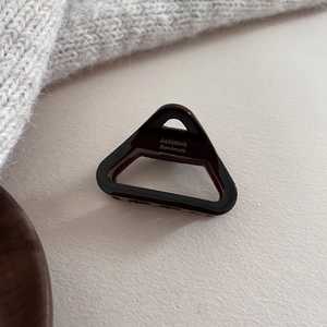 Détail de la pince à cheveux triangulaire en acétate écaille avec logo doré gravé