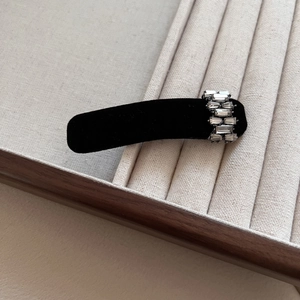Close-up of black velvet hair clip with premium crystal rhinestones on a display tray