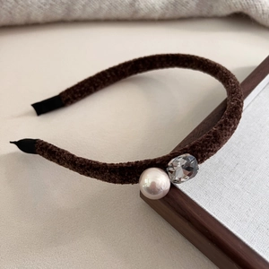 Dettaglio macro del cerchietto in velluto marrone con perla e strass di cristallo