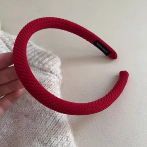 Dettaglio del cerchietto lavorato a maglia rosso con etichetta fatta a mano su sfondo morbido