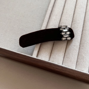 Close-up of elegant black velvet hair clip with five rectangle rhinestones on display