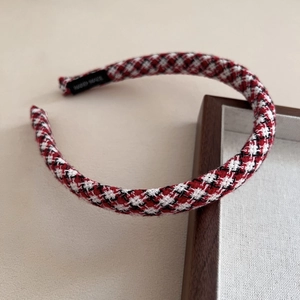 Dettaglio di un cerchietto in tweed a scacchi rossi e neri con trama intrecciata classica