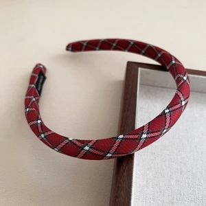 Dettaglio di un cerchietto in tessuto scozzese rosso con trama intrecciata e stile retrò