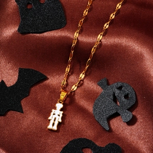 Detail view of gold lip chain with a white skeleton ghost pendant for Halloween style