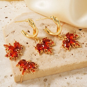 Elegante conjunto de pendientes de hoja de arce con circonitas rojas en metal dorado