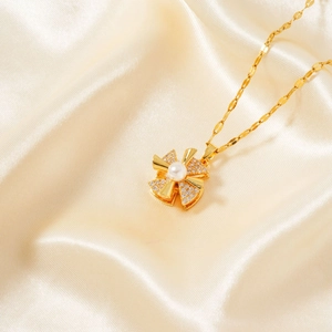 Detailed view of a gold flower pendant necklace with central pearl and pavé crystals