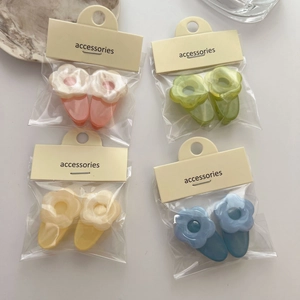Lot de quatre paires de barrettes à fleurs colorées au fini crème sur fond blanc