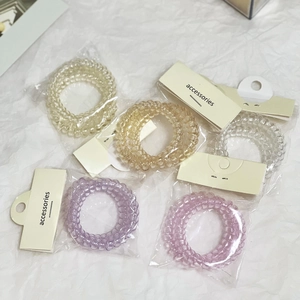 Set di cinque elastici per capelli colorati a spirale su confezione in carta crema