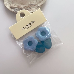 Détail de pinces à cheveux fleurs bleues avec pétales en acrylique sur carte