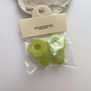 Gros plan de deux barrettes à fleurs vertes sur un support en carton avec texte accessoire