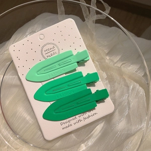 Vue macro de trois barrettes à cheveux vert mat sur un emballage élégant et soigné