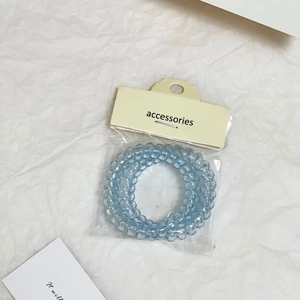 Dettaglio di un elastico per capelli a spirale blu in confezione regalo trasparente