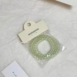 Dettaglio dell'elastico per capelli a spirale verde chiaro in resina con confezione