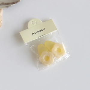 Gros plan de barrettes à fleurs jaune crème minimalistes dans un emballage de détail