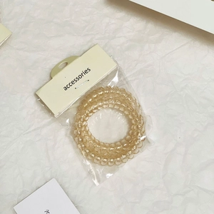 Tre elastici a spirale per capelli color champagne traslucido su fondo di carta bianca